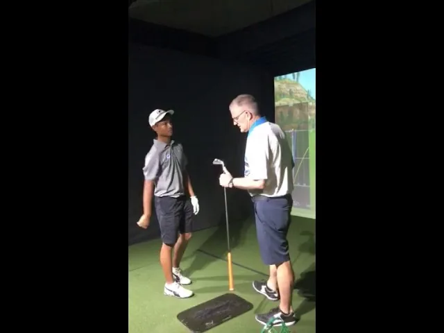 The coach with a young golfer and an iron