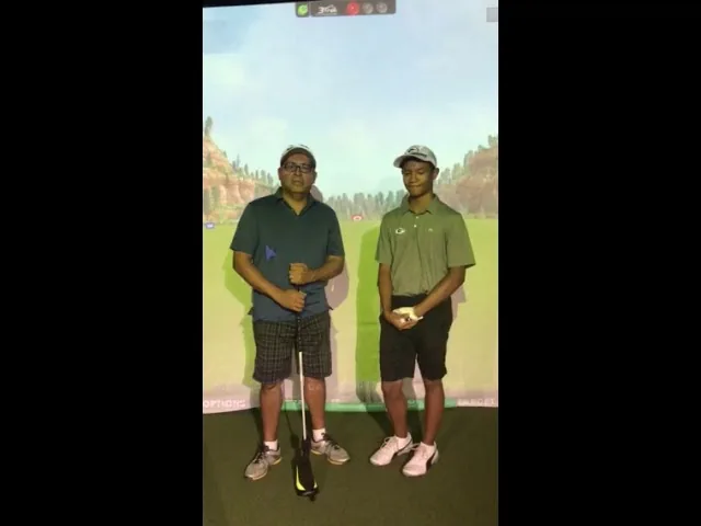 Two golfers in front of the simulator screen